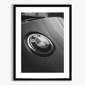 Puede incluir: Impresi&oacute;n enmarcada en blanco y negro que presenta un primer plano de un emblema de BMW. El emblema es circular con un borde plateado y el logotipo de BMW en el centro. El fondo es una superficie negra brillante.