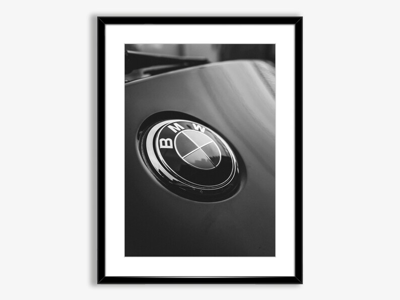 Puede incluir: Impresi&oacute;n enmarcada en blanco y negro que presenta un primer plano de un emblema de BMW. El emblema es circular con un borde plateado y el logotipo de BMW en el centro. El fondo es una superficie negra brillante.