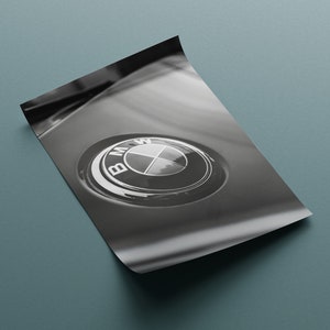 Puede incluir: Impresi&oacute;n en blanco y negro de un emblema de BMW. El emblema es circular, con el logotipo de BMW en el centro. La impresi&oacute;n est&aacute; en una hoja de papel, con una esquina ligeramente doblada.
