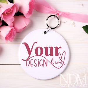 May include: White round ceramic ornament with a pink ribbon and a silver key ring. The ornament has the text "Your Design here" in pink.