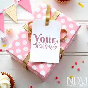 May include: Pink gift box with white polka dots and a gold ribbon. A white gift tag with the text "Your Design here" is attached to the box.