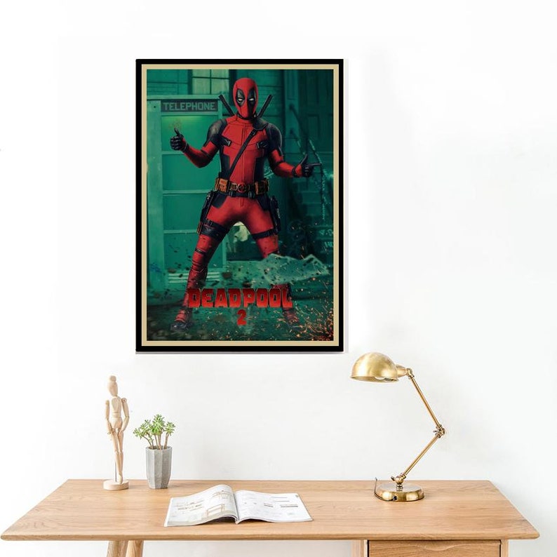 Puede incluir: P&oacute;ster enmarcado con Deadpool con un disfraz rojo y negro, posando con los pulgares hacia arriba. El p&oacute;ster tiene la palabra "DEADPOOL" en rojo, con un fondo verde y marr&oacute;n. El p&oacute;ster est&aacute; en un marco negro.
