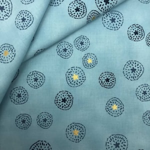 May include: A blue fabric with a repeating pattern of dark blue circles with a small star in the centre. The circles have a gold outline.
