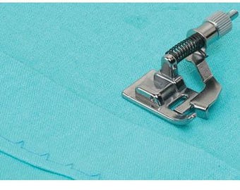May include: A silver-colored sewing machine foot with a spring and adjustable screw is positioned on turquoise fabric. The foot is designed to create a decorative edge on the fabric. The fabric has a stitched edge.