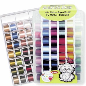 May include: A clear plastic box containing 80 spools of rayon thread in a variety of colours. The box also includes two larger spools of thread for bobbins. The label on the box reads "Rayon Box 80 x 200 m - Rayon No. 40 2 x 1500 m - Bobbinfil".