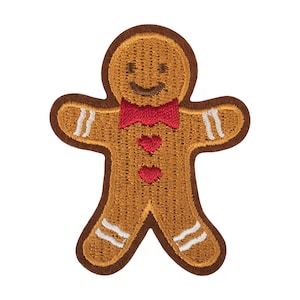 May include: Embroidered gingerbread man patch with a brown outline, tan body, and red bow tie and heart accents. The patch features white stripes on the arms and legs, and a smiling face. Ideal for festive crafts and clothing.