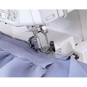 May include: A close-up of a sewing machine with a foot attached to the needle. The machine is sewing a piece of light blue fabric.