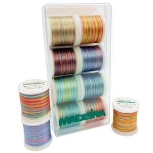 May include: A clear plastic box containing eight spools of colourful Madeira embroidery thread. The spools are arranged in two rows of four. The spools are all different colours, including red, orange, yellow, green, blue, purple, and brown. The spools are labelled "Madeira" and "www.madeira-garn.co.uk".
