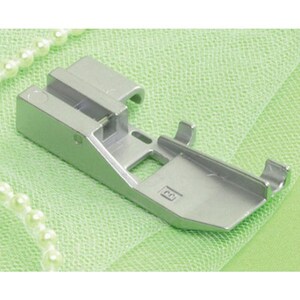 May include: A silver sewing machine presser foot. The foot is rectangular with a flat base and a raised section with a curved edge. It is designed to attach to a sewing machine and guide fabric during stitching.