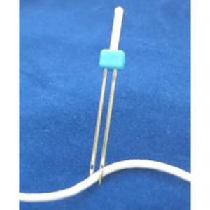 May include: A sewing machine needle with two parallel needles and a turquoise plastic piece. The silver needles are positioned above a white thread against a blue background.