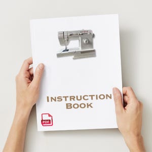 May include: A white instruction manual for a sewing machine. The cover features a photo of the sewing machine and the text "INSTRUCTION BOOK" in brown letters. A red PDF icon is in the bottom left corner.