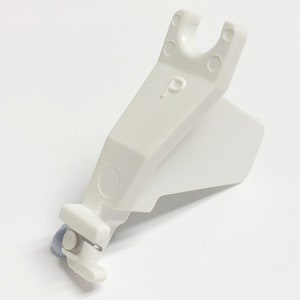 May include: White plastic sewing machine foot with a small blue roller and a letter "P" printed on the side.