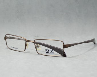 ADOLFO DOMINGUEZ 54224 123. Vintage Titanium prescription glasses. Optim Spain 2010s. New Brand, Urworn. Warp square narrow. Brown. Sport