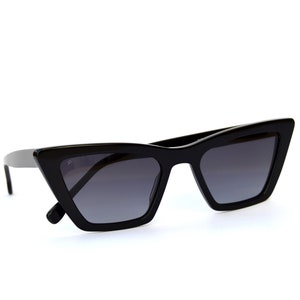 May include: Black cat-eye sunglasses with a sharp, angular frame and dark gray lenses.