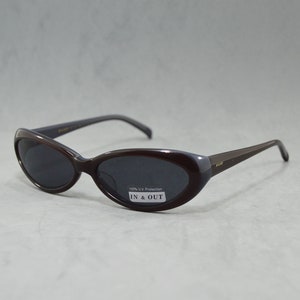 May include: Brown oval-shaped sunglasses with dark lenses. The sunglasses have a label that reads "100% UV Protection IN & OUT".
