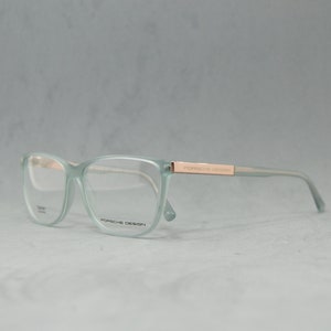 May include: A pair of light green eyeglasses with a rose gold frame and the text "PORSCHE DESIGN" on the side.