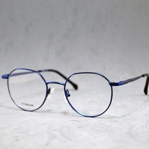 Op de afbeelding: Blauwe titanium gemonteerde bril met ronde glazen.
