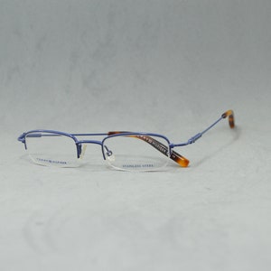May include: Blue metal frame eyeglasses with clear lenses. The arms are brown tortoise shell. The text "Tommy Hilfiger" and "Stainless Steel" is printed on the frames.
