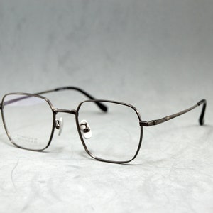 May include: A pair of silver-toned metal spectacles with square frames and clear lenses.