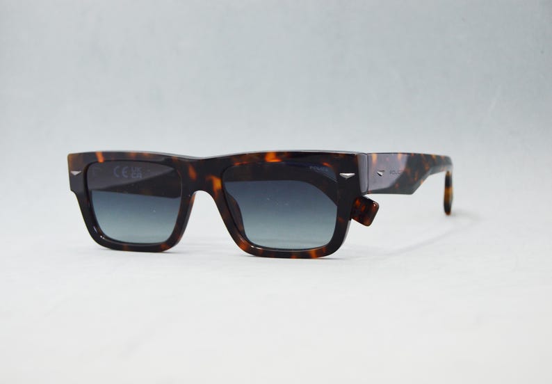 Puede incluir: Gafas de sol rectangulares con montura de patr&oacute;n de carey en marr&oacute;n y negro y lentes degradadas oscuras. La montura incluye detalles met&aacute;licos en tono plateado en las esquinas exteriores y a lo largo de las patillas.