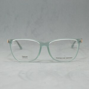 May include: A pair of light green eyeglasses with a titanium frame and gold accents. The glasses have a square shape with rounded edges and say "Porsche Design" on the right temple.