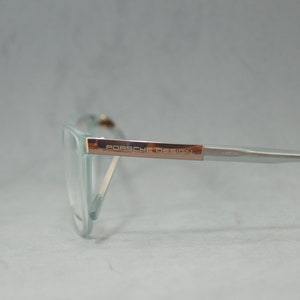 May include: A pair of light blue eyeglasses with a rose gold frame and the text "PORSCHE DESIGN" on the side.