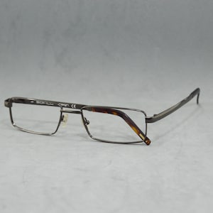 Peut inclure: Une paire de lunettes en métal argenté avec une monture rectangulaire et des accents en écaille de tortue brune.
