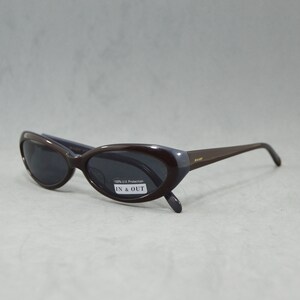 May include: Brown oval-shaped sunglasses with dark lenses. The sunglasses have a label that says "100% UV Protection" and "IN & OUT".