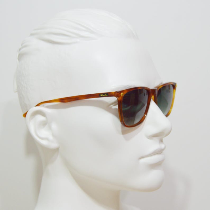 May include: Brown tortoise shell sunglasses with green lenses. The sunglasses are on a white mannequin head.