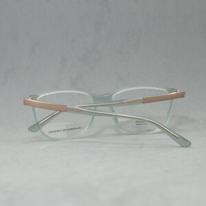 May include: Light blue eyeglasses with a rose gold frame. The frame has a silver metal bridge and arms.