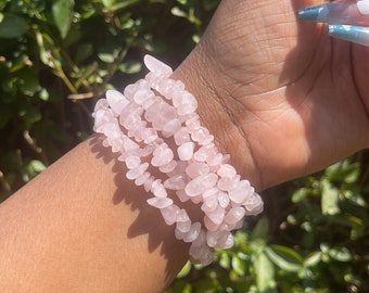 May include: A set of three pink rose quartz chip bracelets. The bracelets are made of small, irregular pieces of rose quartz that are strung together on elastic.