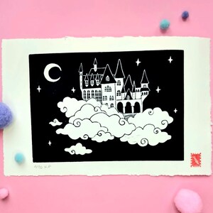 Peut inclure: Une linogravure en noir et blanc représentant un château flottant sur des nuages contre un ciel nocturne avec un croissant de lune et des étoiles. L'impression a un fond blanc cassé texturé et un timbre rouge dans le coin.