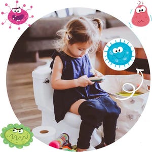 May include: A young child sits on a white toilet seat with a white and beige storage bin next to them. The child is wearing a dark blue dress and black leggings. The storage bin has a cartoon germ on it with a happy face.