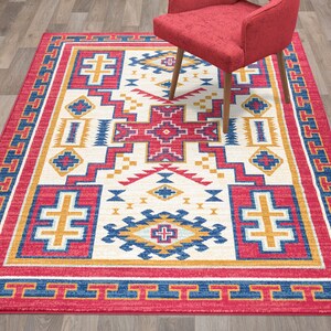 May include: A Southwestern-style area rug with a white background and a geometric pattern in shades of red, blue, and yellow. The rug has a red border with a blue and yellow geometric pattern.