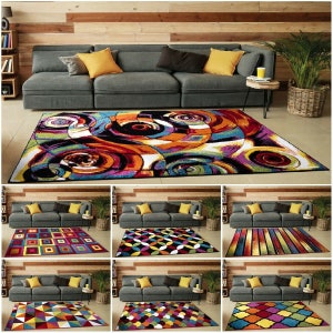 May include: A collection of ten colorful area rugs with abstract, geometric, and striped patterns. The rugs are displayed on a wooden floor in front of a gray couch.