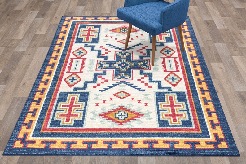 May include: A Southwestern-style rug with a geometric pattern in shades of blue, red, yellow, and white. The rug has a border with a repeating pattern.