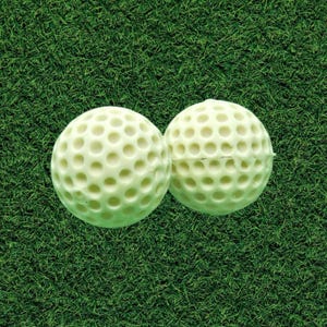 May include: Two off-white golf balls featuring a uniform dimpled surface texture. Each ball is spherical and displays a consistent pattern of circular indentations across its entire exterior, showcasing the standard design of equipment used in golf.