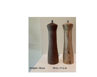 Op de afbeelding: Twee houten pepermolens, één donkerbruin en één lichtbruin, staan naast elkaar. De donkerbruine molen is effen, terwijl de lichtbruine zichtbare houtnerf heeft. Elk is ongeveer 25,4 cm hoog met een basis van 6 cm.