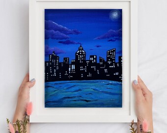 Peut inclure: Une peinture encadrée d'un horizon urbain de nuit. La ville est en silhouette contre un ciel bleu foncé avec quelques nuages. Une petite lune blanche est visible dans le coin supérieur droit de la peinture. L'eau au premier plan est d'un bleu foncé.