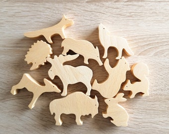 May include: A set of wooden animal puzzle pieces, including a fox, wolf, deer, moose, hedgehog, squirrel, rabbit, and bison. The pieces are all natural wood color and have a smooth, unfinished surface.
