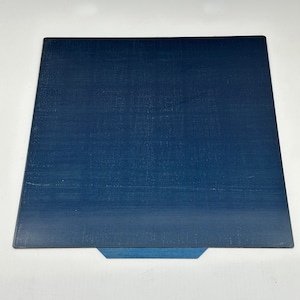 Könnte beinhalten: Eine weiße Keramiktasse mit schwarzem Henkel und dem Text "But First, Coffee" in fetter, schwarzer Schrift. Die Tasse steht vor einem verschwommenen Hintergrund, der eine gemütliche Umgebung suggeriert.