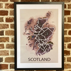 May include: A framed map of Scotland with a watercolor-style design. The map is in shades of purple and brown, with white lines representing roads and cities. The word "SCOTLAND" is printed in black at the bottom of the map.