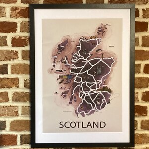 May include: A framed print of a map of Scotland with a watercolor-style background. The map shows major cities and landmarks, with the word "SCOTLAND" printed at the bottom.