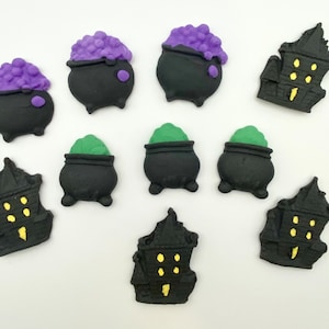 May include: A collection of Halloween-themed decorations. The image features black cauldrons with purple and green bubbling potions, and black haunted houses with yellow windows and doors. These decorative pieces are perfect for Halloween.