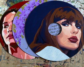 May include: Three painted vinyl records. One features a portrait with a red background, another has purple flowers, and the third has a portrait with brown hair and the text "this is me trying illicit affairs".