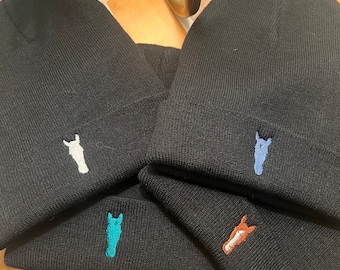 May include: Four black knit beanies, each featuring a small embroidered horse head design on the cuff. The horse head embroidery colors are white, light blue, teal, and a combination of brown and white.
