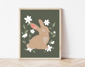 May include: A framed art print featuring a tan bunny surrounded by white flowers and green leaves against a dark green background. The bunny has pink inner ears and is in a seated position. The artwork is in a wooden frame.