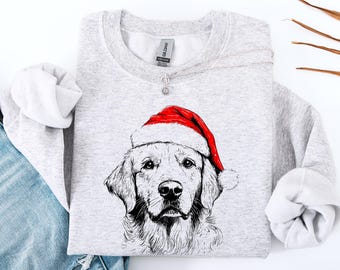 May include: A light grey sweatshirt with a detailed illustration of a Golden Retriever wearing a red Santa hat. The dog's face is the focal point, with a detailed black and white drawing. The sweatshirt has long sleeves and a crew neck.