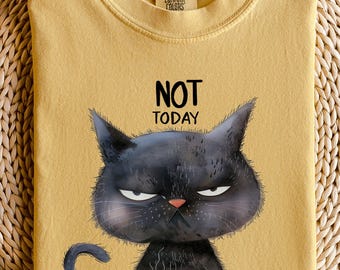 Könnte beinhalten: Senfgelbes T-Shirt mit dem Text "NOT TODAY" und einer Illustration einer grummeligen schwarzen Katze, die eine Kaffeetasse hält. Das Shirt besteht aus weichem Material und hat einen Rundhalsausschnitt. Die Marke "Comfort Colors" ist am Kragen sichtbar.