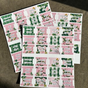 May include: Sheets of Bible book tabs with floral and gingham patterns. The tabs are labeled with book names like Genesis, Exodus, and Proverbs. The tabs are in pink, green, and white.
